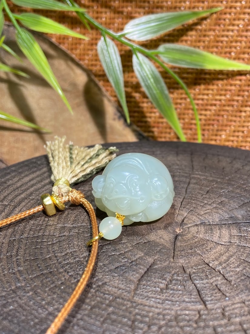 An Excellent Agate 'Chi-Dragon' Pendant: A finely carved Hetian jade pendant of Xinjiang Youqing (oily green) material, carved as a pig, a symbol of wealth and abundance. The jade is of fine, oily texture with a smooth, warm finish. The pend