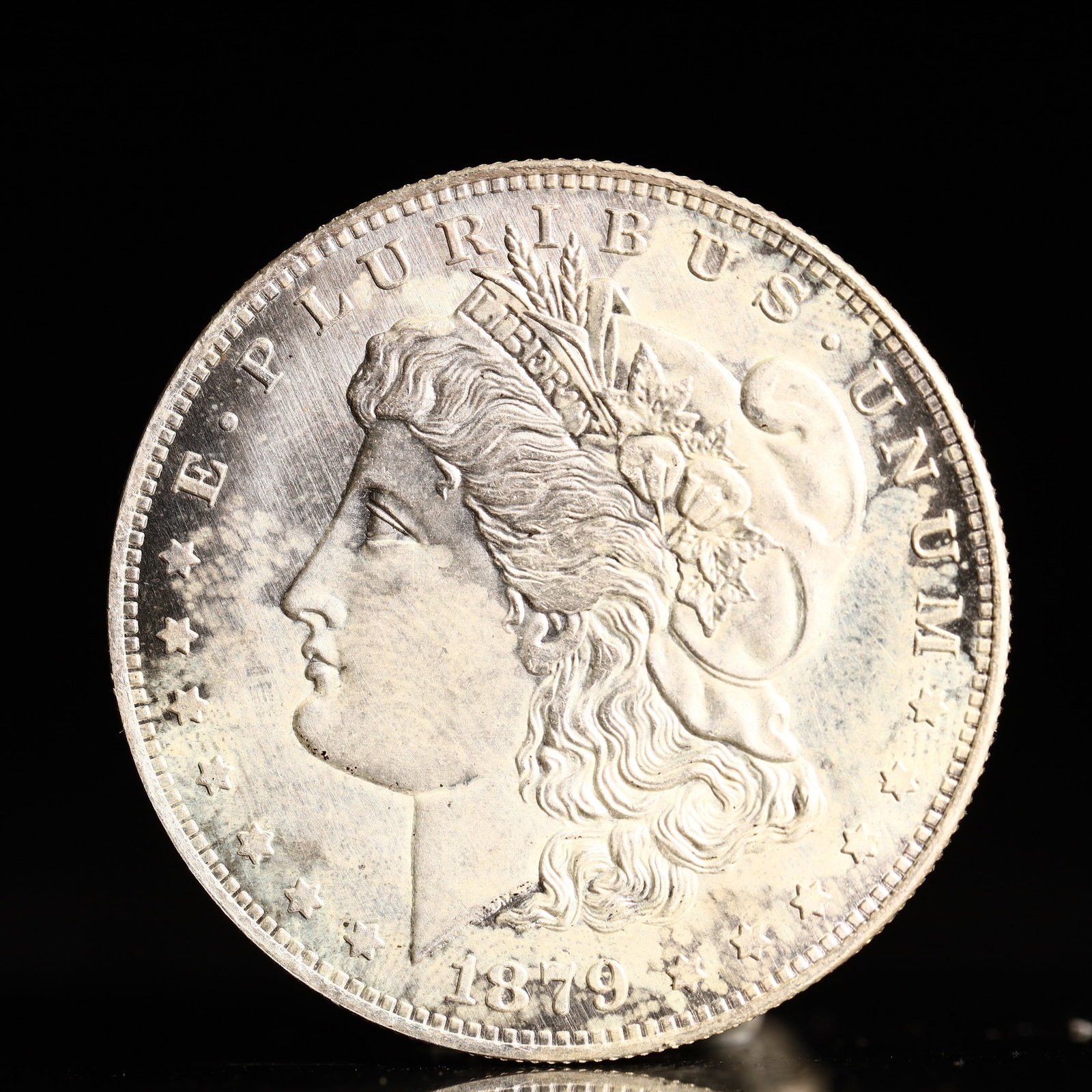 USA Morgan Dollar 1879 Coin: Obv: profile bust with date below and E PLURIBUS UNUM legend and stars around. Rev: eagle with In God we trust above within wreath with UNITED STATES OF AMERICA ONE DOLLAR legend. IN GOD WE TRUST / LI