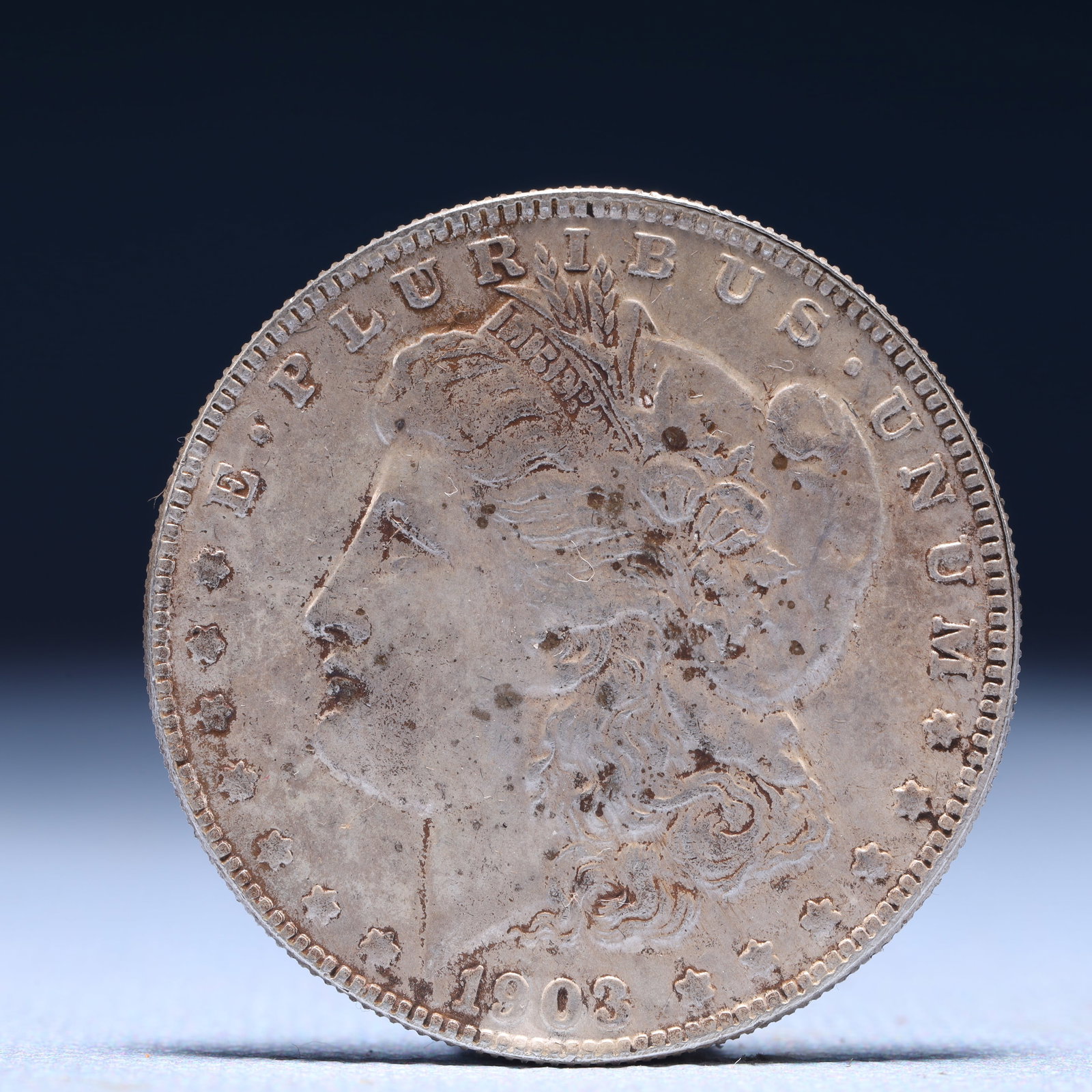 USA Morgan Dollar 1903 Coin: Obv: profile bust with date below and E PLURIBUS UNUM legend and stars around. Rev: eagle with In God we trust above within wreath with UNITED STATES OF AMERICA ONE DOLLAR legend. IN GOD WE TRUST / LI