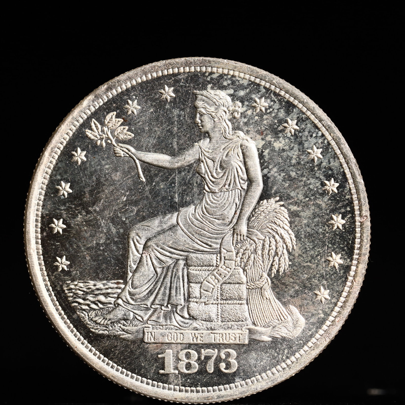 USA Trade Dollar 1873 Coin: American coin. Obverse: Liberty seated on a pedestal facing the sea to the left holding olive branches surrounded by 13 stars. IN GOD WE TRUST / LIBERTY / 1873. Reverse: An eagle holding branches