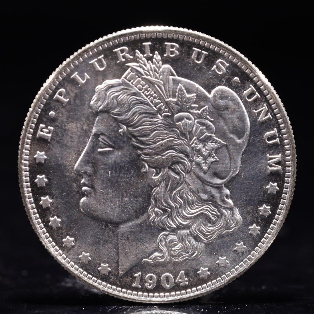 USA Morgan Dollar 1904 Coin: Obv: profile bust with date below and E PLURIBUS UNUM legend and stars around. Rev: eagle with In God we trust above within wreath with UNITED STATES OF AMERICA ONE DOLLAR legend. IN GOD WE TRUST /