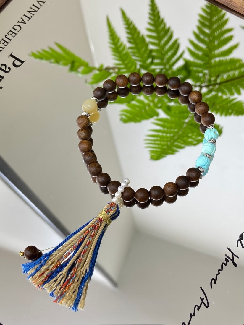 A Finely Carved Hetian Jade Bracelet with Turquoise: A finely carved Hetian jade bracelet of Qiemo sugary-white quality, composed of 7mm beads, accompanied by turquoise and agarwood beads. The bracelet measures 7mm in bead diameter. 且末