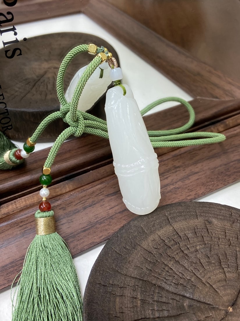 A Finely Carved Hetian Jade 'Yangzhi' White Jade 'Bamboo' Pendant: A finely carved Hetian jade pendant of 'yangzhi' (mutton-fat) white quality, carved as a bamboo knot, a symbol of steady growth and success, suitable as a car hanging or handpiece. The jade is of
