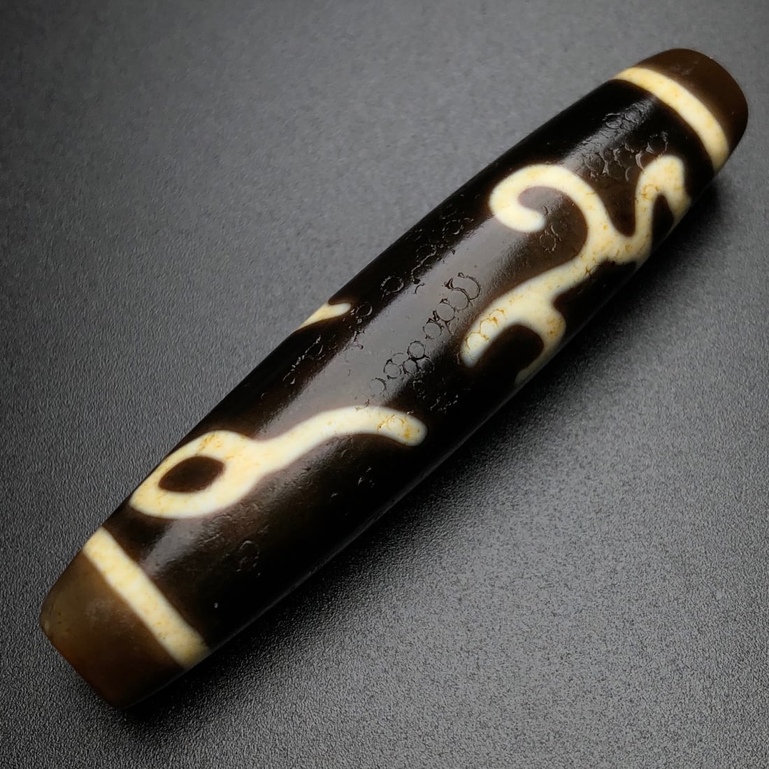 An Exquisite Old Material Irregular Lotus Three-Eyed Dzi Bead: An Exquisite Old Material Irregular Lotus Three-Eyed Dzi Bead. Rich oily patina, unique bead form, clear totem. Size: 58mm×13mm×12mm; weight: 14.1g.