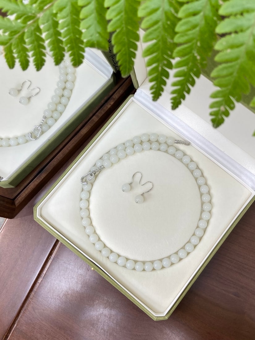 A Finely Carved Hetian Jade 'Tiantai' 'Yangzhi' White Jade Necklace: A finely carved Hetian jade necklace of Tiantai origin, of 'yangzhi' (mutton-fat) white quality, composed of round beads of 10mm diameter, accompanied by 925 silver earrings. The necklace measures 10m
