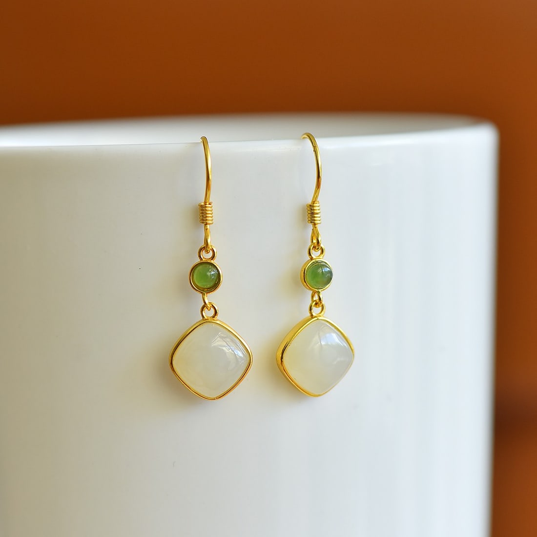 A Pair of Sterling Silver and White Jade Square Drop Earrings: A pair of sterling silver drop earrings, each set with a white jade of square form, Sise: 8mm×8 mm. 纯银镶白玉方形耳坠；主石