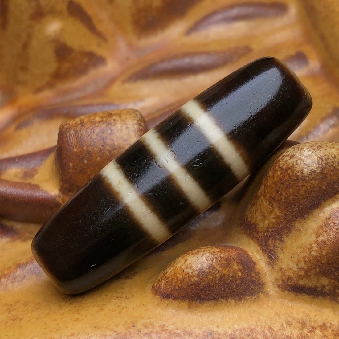 An Exquisite Old Material Three-Line Dzi Bead: An Exquisite Old Material Three-Line Dzi Bead. Rich oily patina, antique and beautiful, clear line patterns. Size: 35mm×11mm; weight: 7.2g. 一件老料三线天
