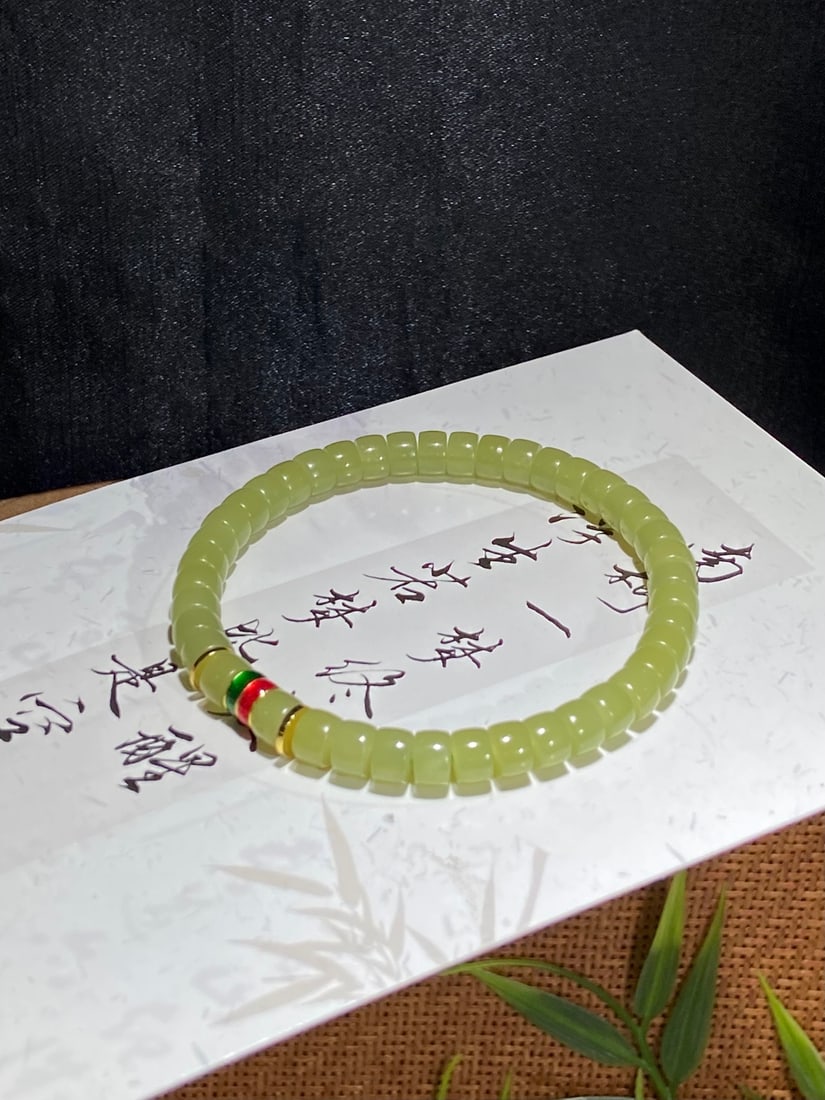 A Finely Carved Hetian Jade 'Huangkou' Bracelet: A finely carved Hetian jade bracelet of 'huangkou' (yellow-mouth) quality, of 'tablet' form, measuring 6mm by 4mm. The jade is of fine, warm texture with a soft, yellow hue. The bracelet measures 6mm 