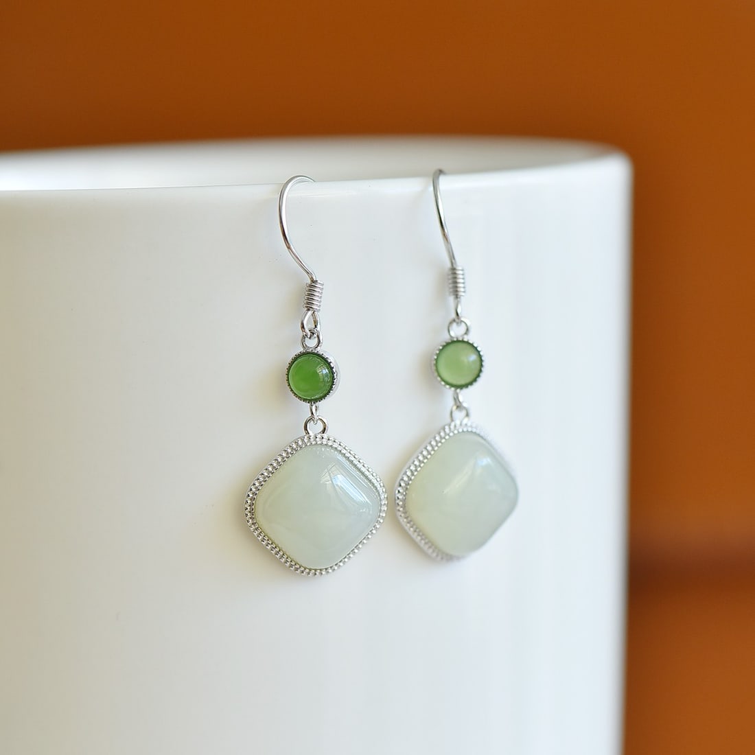 A Pair of Sterling Silver and White Jade Square Drop Earrings: A pair of sterling silver drop earrings, each set with a white jade of square form, Sise: 10mm×10 mm. 纯银镶白玉方形耳坠；主ĳ