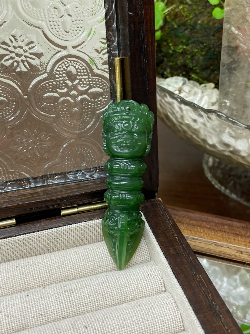 A Finely Carved Hetian Jade 'Russian' Spinach-Green 'Vajra' Pendant: A finely carved Hetian jade pendant of Russian origin, of spinach-green tone with a red skin, carved as a vajra (dorje), a symbol of indestructible wisdom and power. The jade is of fine, rich color wi