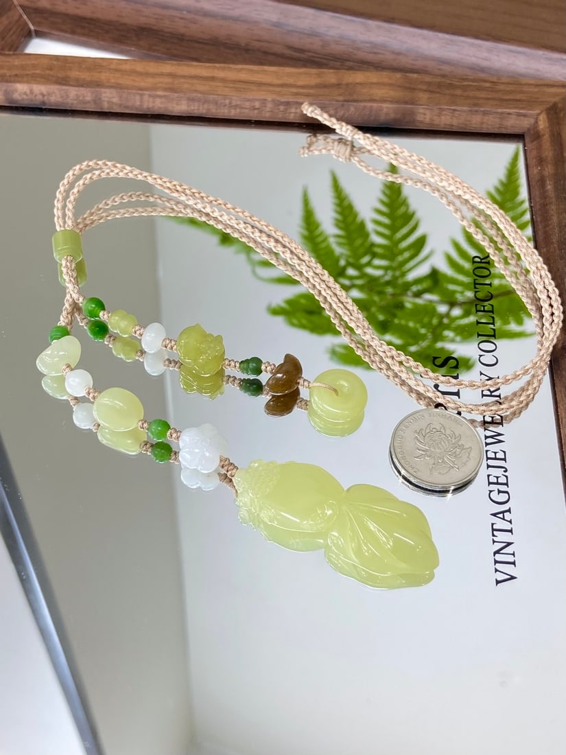 A Finely Carved Hetian Jade 'Ruoqiang Huangkou' Goldfish Pendant: A finely carved Hetian jade pendant of Ruoqiang huangkou (yellow-mouth) quality, carved as a goldfish, a symbol of abundance and prosperity. The jade is of fine, icy texture with a smooth, luminous fi