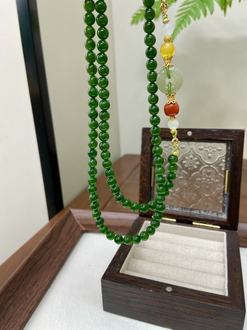 A Finely Carved Hetian Jade 'Spinach-Green' Necklace: A finely carved Hetian jade necklace of spinach-green quality, composed of 108 round beads of 6mm diameter, accompanied by carnelian, amber, and qingshui beads. The necklace measures 6mm in bead diame