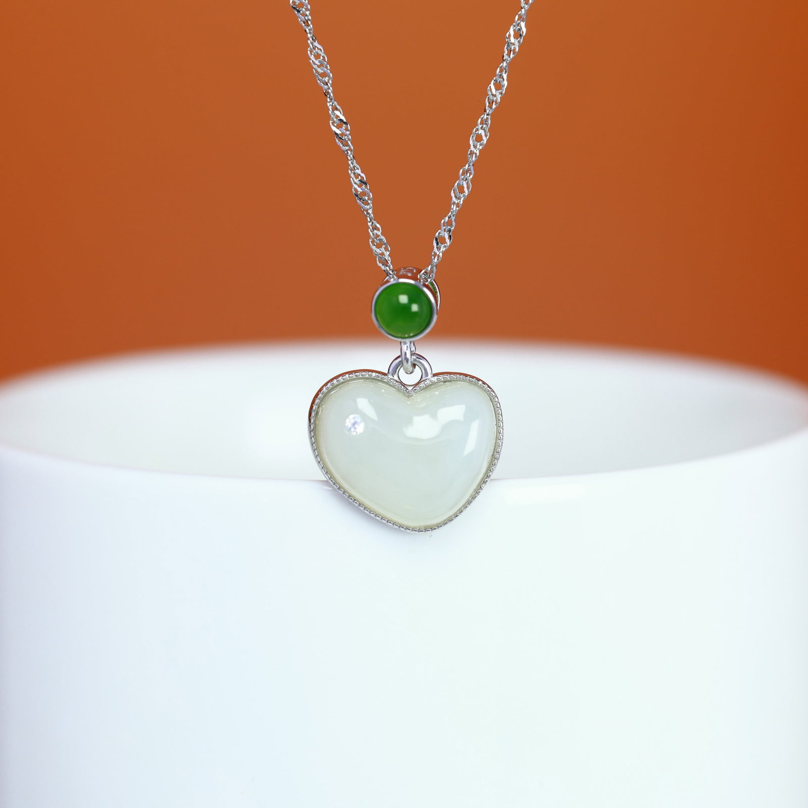 A Sterling Silver and White Jade Heart Pendant: A sterling silver pendant set with a white jade heart, Sise: 11mm×14 mm. 纯银镶白玉心形吊坠；主石为白玉&#