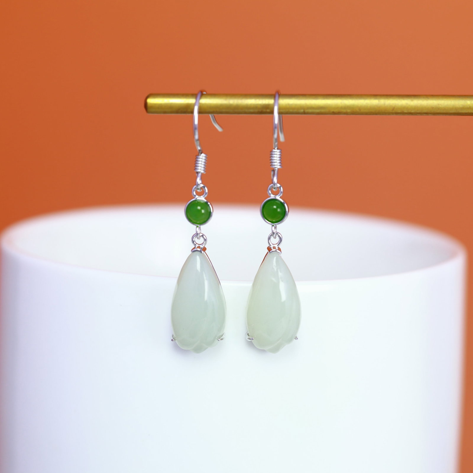 A Pair of Sterling Silver and White Jade Magnolia Drop Earrings: A pair of sterling silver drop earrings, each set with a white jade magnolia, Sise: 8mm×15 mm. 纯银镶白玉玉兰花耳坠；主