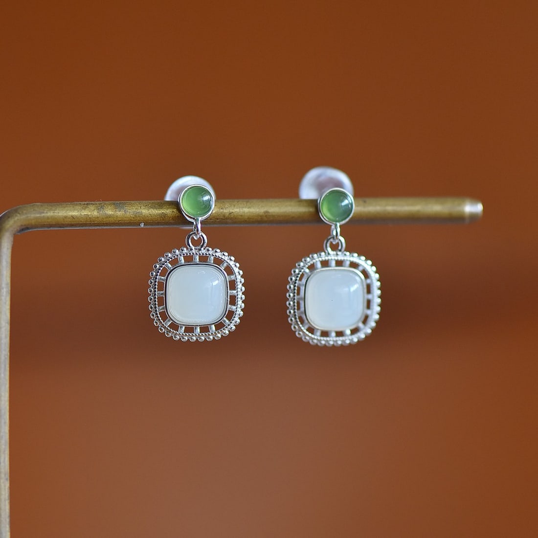 A Pair of Sterling Silver and White Jade Square Stud Earrings: A pair of sterling silver stud earrings, each set with a white jade of square form, Sise: 6mm×6 mm. 纯银镶白玉方形耳钉；主石