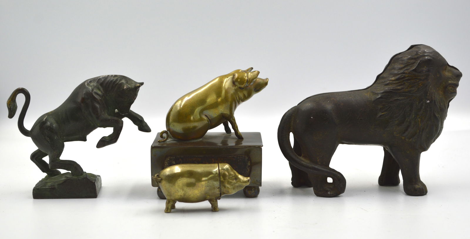 Four Sculptures: One Cast Iron Lion Bank, Three Miniature Metal Animal Figures: One Cast Iron Lion Bank. Three Miniature Metal Animal Figures Lion bank measures: 5.5 inches x 4 inches high One Bigger brass pig figure sitting on a matchbox One miniature brass pig match Vesta with