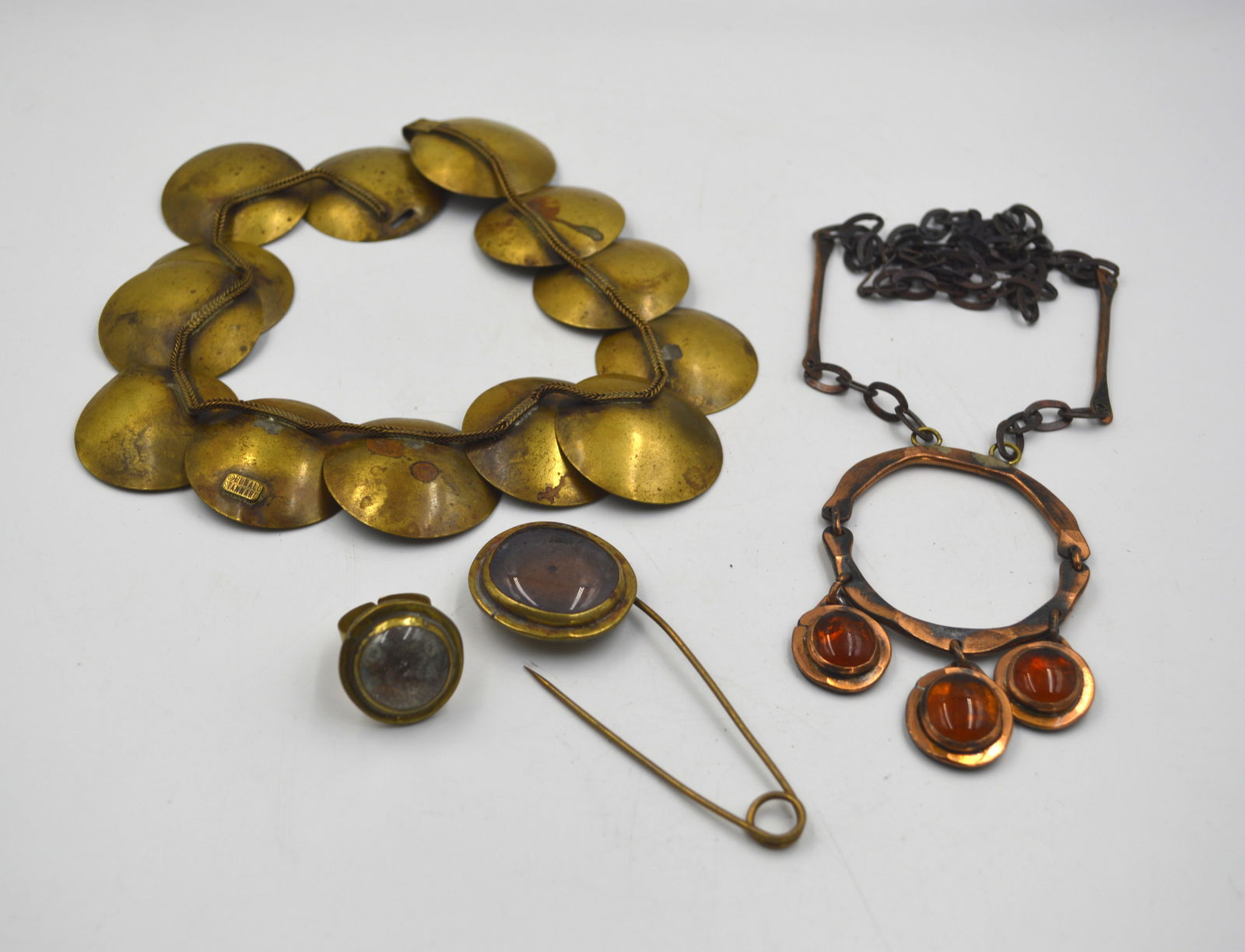 Modernist Canadian Jewelry: A lot consisting of 1970s handmade necklace by Donald Stanard. Also includes brass rings and kilt pin and a copper necklace signed.