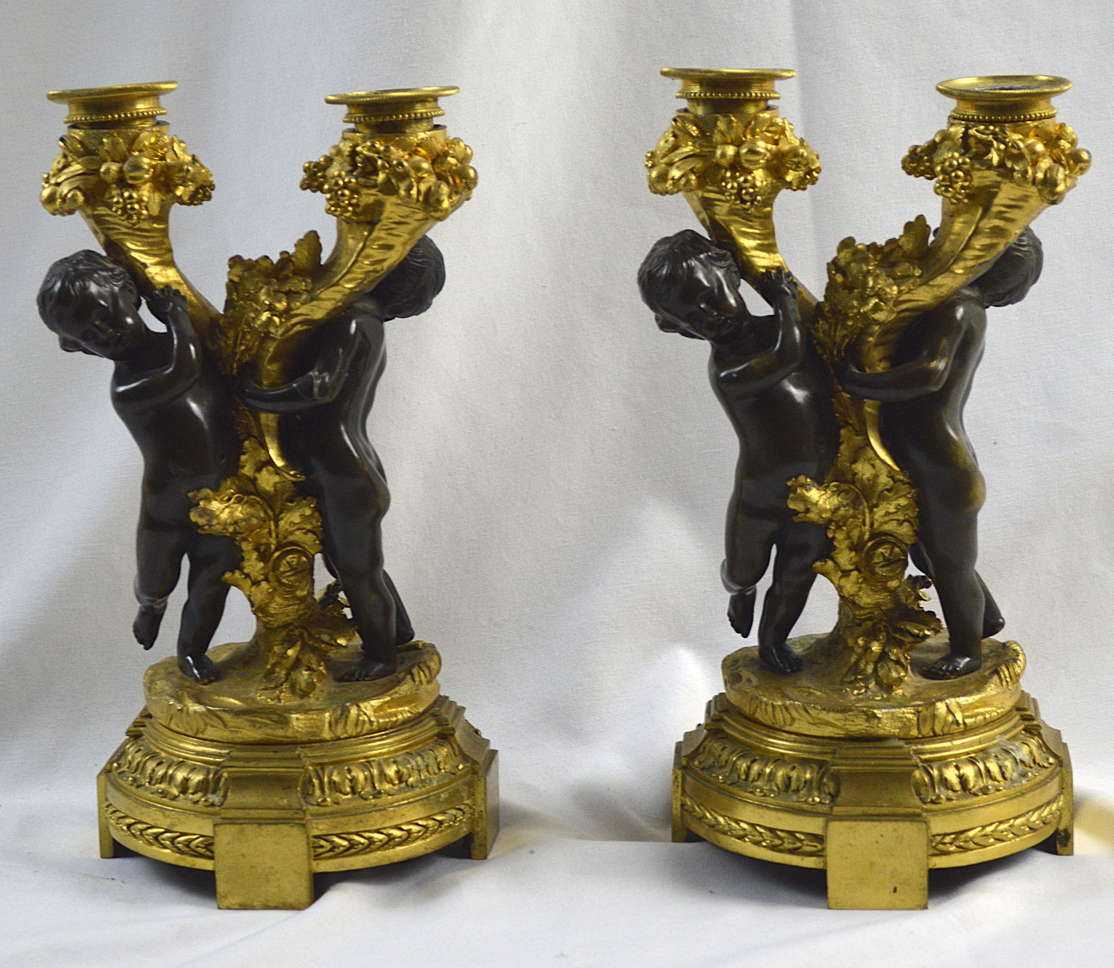 Gilt Bronze Antique Figural Candelabra: French antique gilt Bronze figural candle stick holders. Cherubs with grape motif. Each holder has two branches Measures: 10.5 inches high