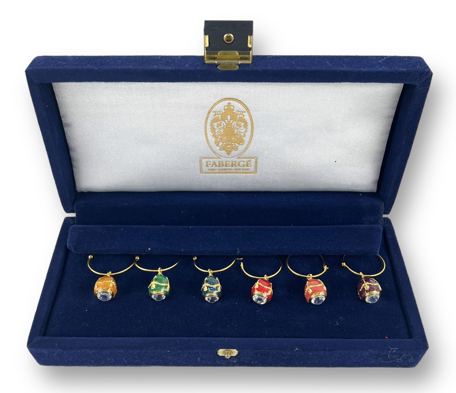 (6) Faberge Egg Wine Charms in Case: Box is 8" wide x 3 1/2" deep x 1 3/4" tall Each charm is 1" across Condition: Wine charms and case are all in very good condition. No issues seen.