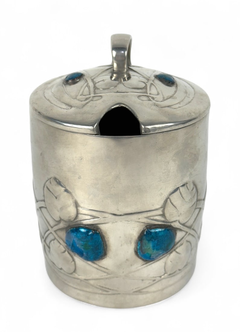 Archibald Knox Tudric Pewter & Enamel Preserve Pot: Marked and numbered "0700" on bottom. Height: 5 1/2" Condition (UPDATED): On the larger left-hand side enamel, there’s a patch where the enamel itself is intact, but the resin coa