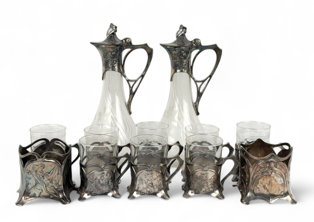 (12pc) WMF Art Nouveau Silverplate Crystal Jug, Cups & Wine Coasters: The cups are marked with the maker’s mark and are numbered on the metal bases. The coasters are marked “WMF G” and numbered “0X 1/0.” The jugs are marked “I/0&