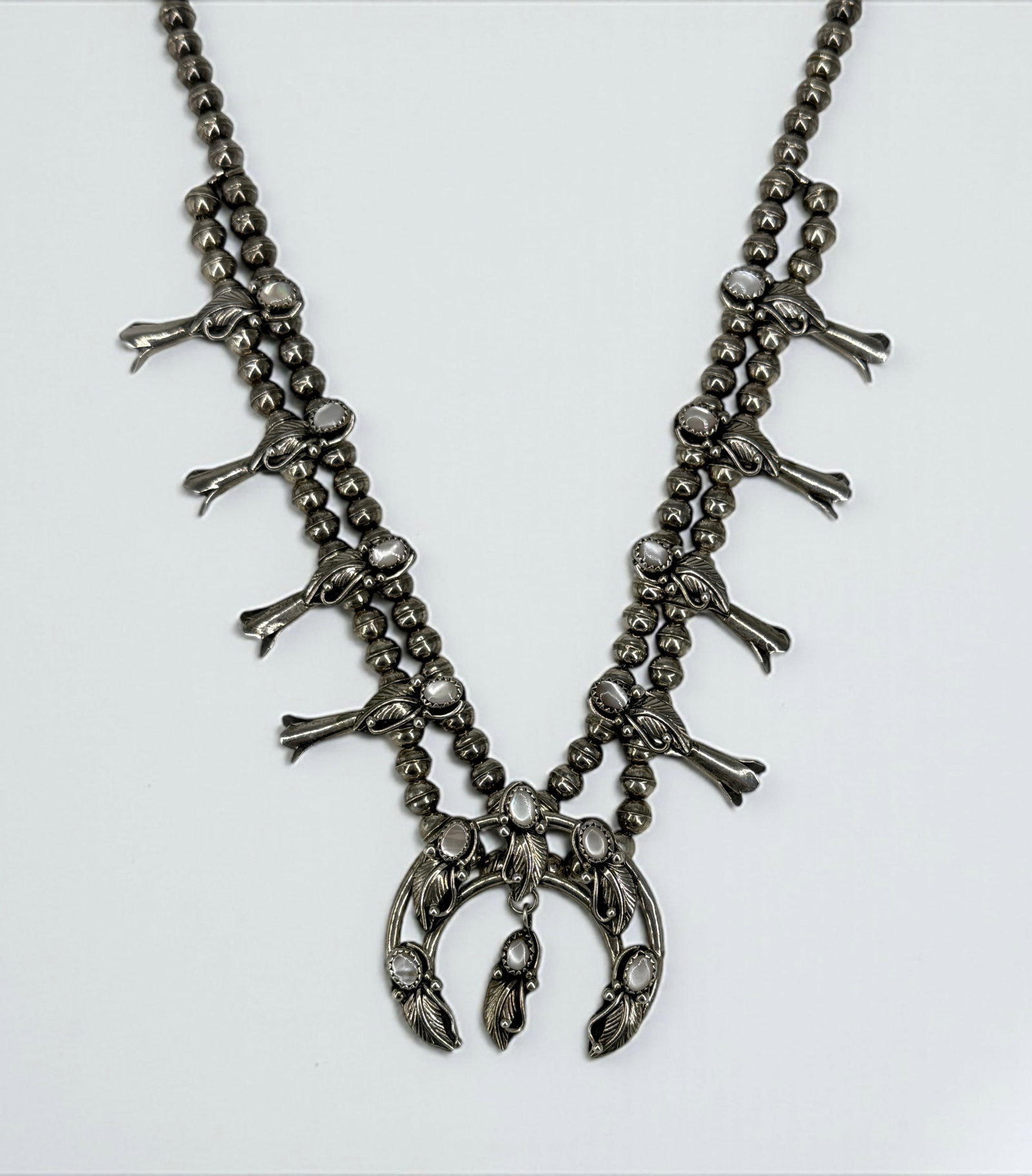 Navajo Sterling Silver & Mother of Pearl Squash Blossom Necklace: Signed "M" Length: 23" Weight: 58g Condition: Light tarnish and minor surface wear consistent with age and use. Overall in good condition.