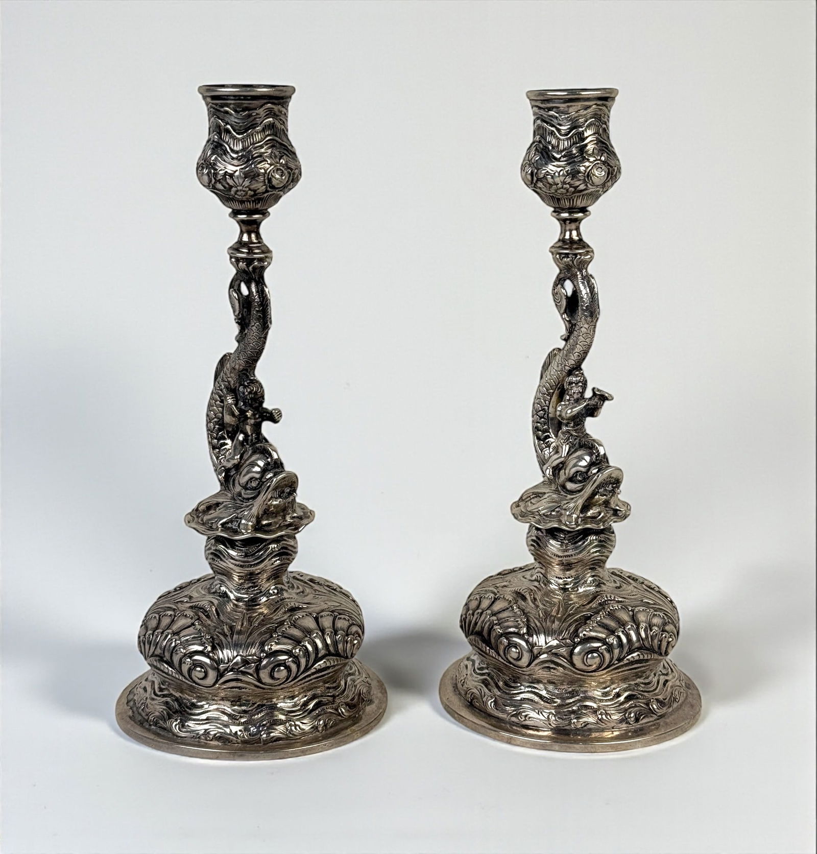 Pair of German 800 Silver Dolphin & Cherub Candlesticks: Height: 9 7/8" Each Total Weight: 26ozt Condition: Good. Some residue at opening. One wobbles at the base. No Monograms