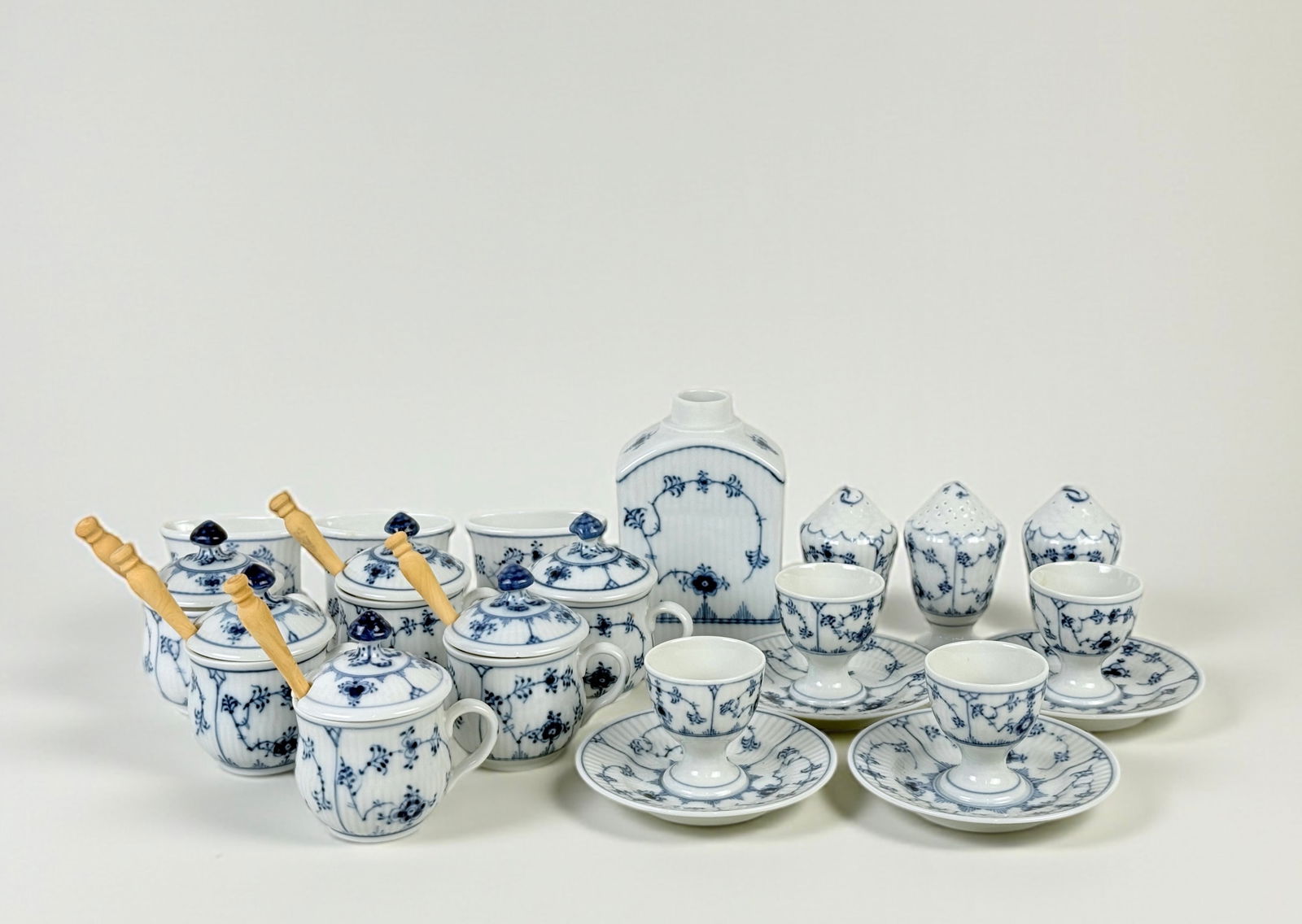 (17pc) Group Of Royal Copenhagen Blue Fluted Porcelain: Group includes: (1) Tea Caddy, 5" (missing the top), (6) mustard cups, one is missing the spoon, (3) Shakers, (4) Egg Cups, (3) Toothpick Holders Condition: Very good wit