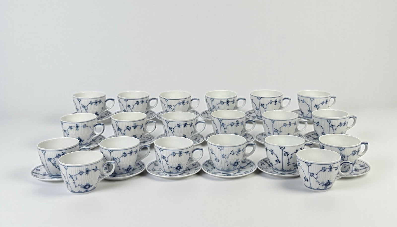 (38pc) Royal Copenhagen Blue Fluted Cups and Saucers: Set includes (20) cups and (18) saucers Cup: 2 3/4"H x 3 1/4" diameter. Condition: One saucer has a small chip on the rim; otherwise, very good with minimal wear.