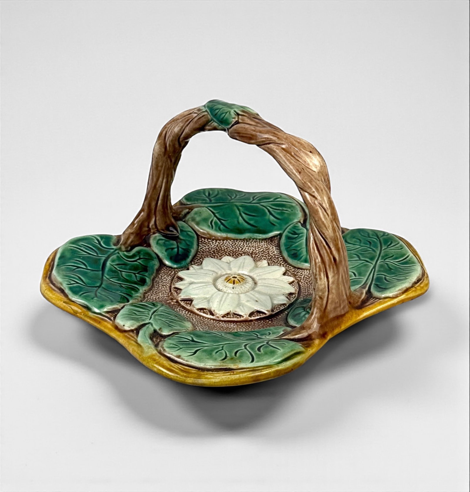 Antique Majolica Handled “Lily" Plate: Dimensions: 5 1/2"T x 7 1/2"W Condition: Very good with no chips or cracks.