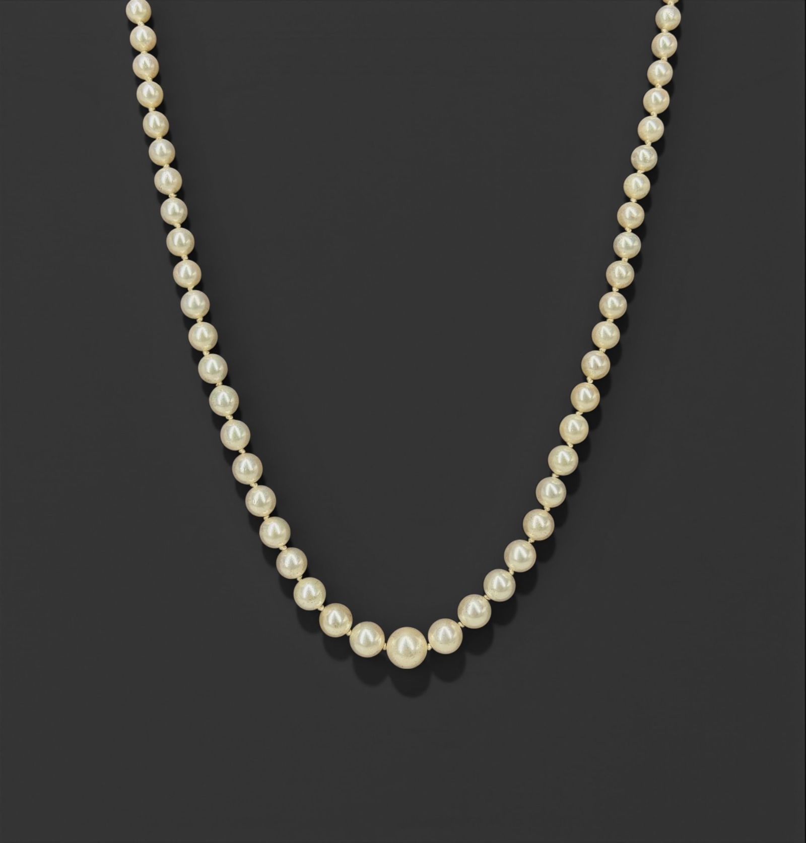 Mikimoto Pearl Necklace W/ 10K Gold Clasp: Graduated strand of cultured pearls, ranging from approximately 3.9 mm at the ends to 9.6 mm at the center; fitted with a white metal fishhook (marquise) clasp set with a small pearl and accent stones