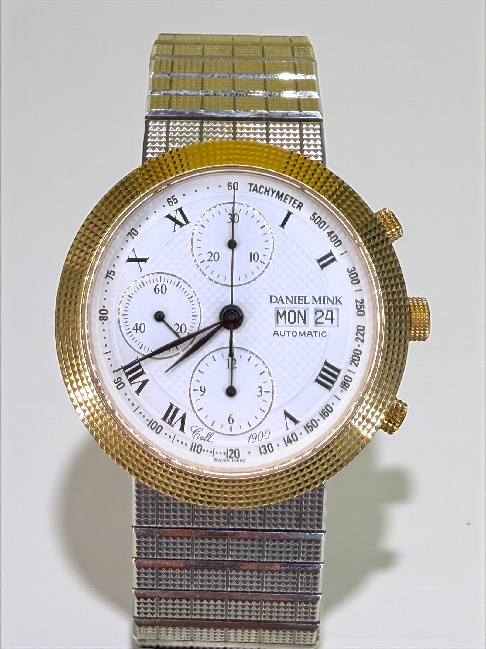 Daniel Mink 18K & Stainless Automatic 40mm Chronograph: "1900s Collection" Day/Date with Valjoux Movement. The bezel has a distinctive 'Clous de Paris' pyramid texture. Dial: White with Black Roman Numerals Bracelet: