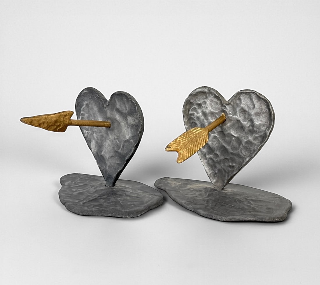 Michael Aram 'Heart & Arrow' Bookends: Signed by the artist on the bottom. Dimensions of one: 6" T x 9" W x 6" D Condition: Both bookends are in good condition with some minor loss of gold finishing to th