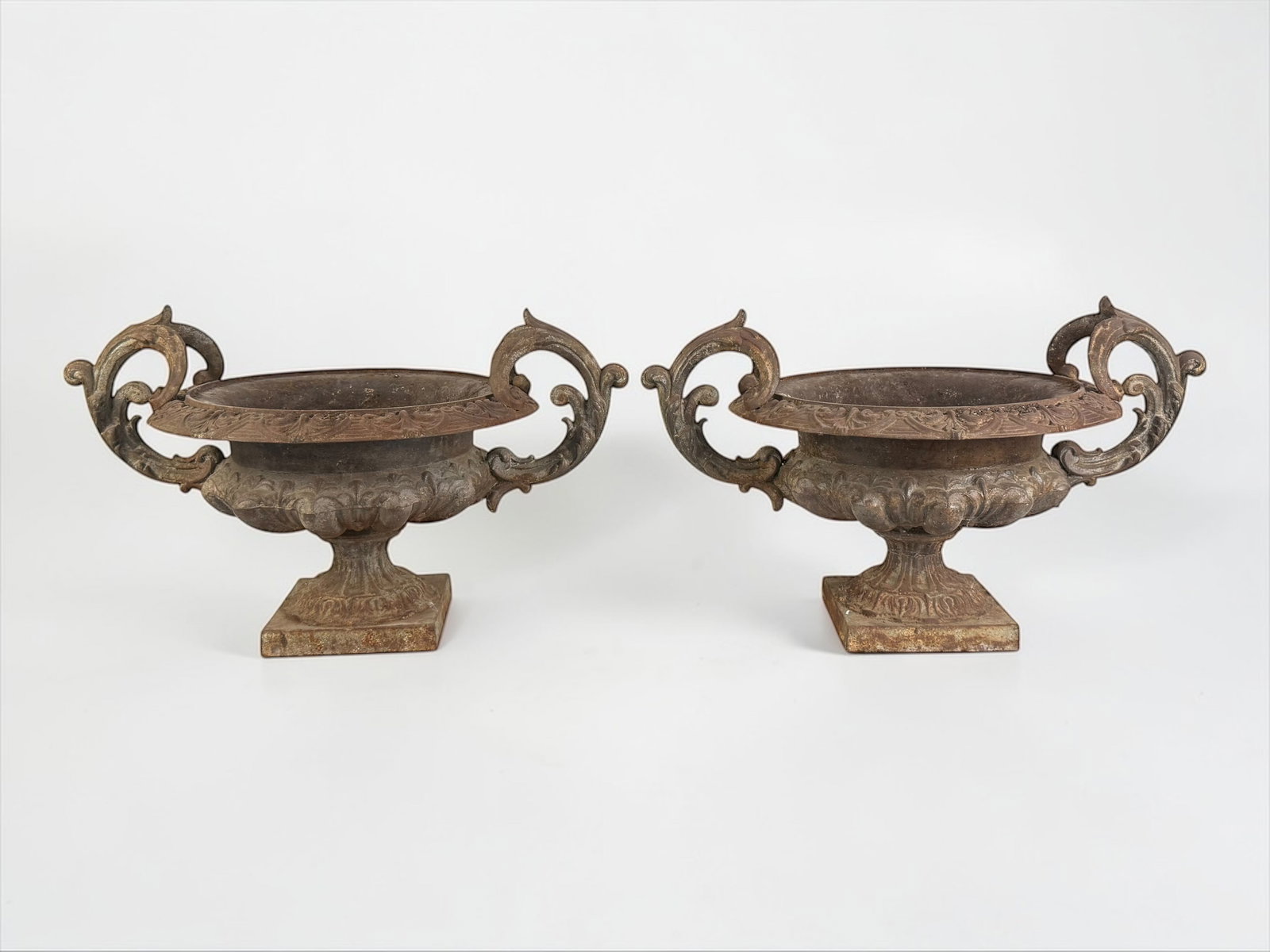Pair of Victorian Double Handled Cast Iron Garden Urns: Dimensions: Width Handle-to-Handle: 26", Interior Width: 10 1/2", Height: 12" Condition: There are a few spots where the metal is corroded through in one of the planters.