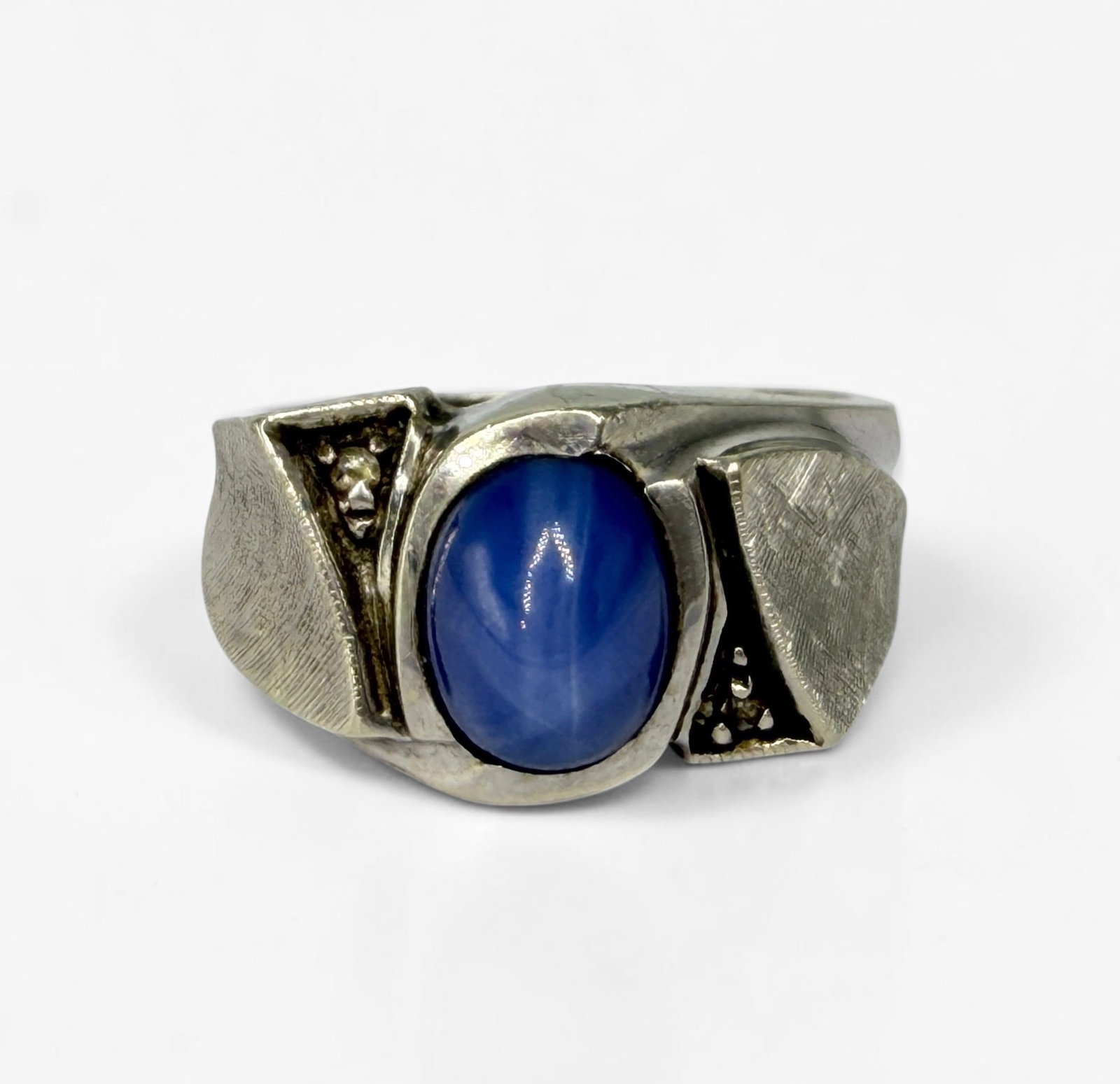 14K White Gold & Synthetic Star Sapphire Ring: Size: 8 Weight: 6.48g Dimensions: 11mm wide band Condition: Minor scratches to the ring; otherwise, in good condition. 