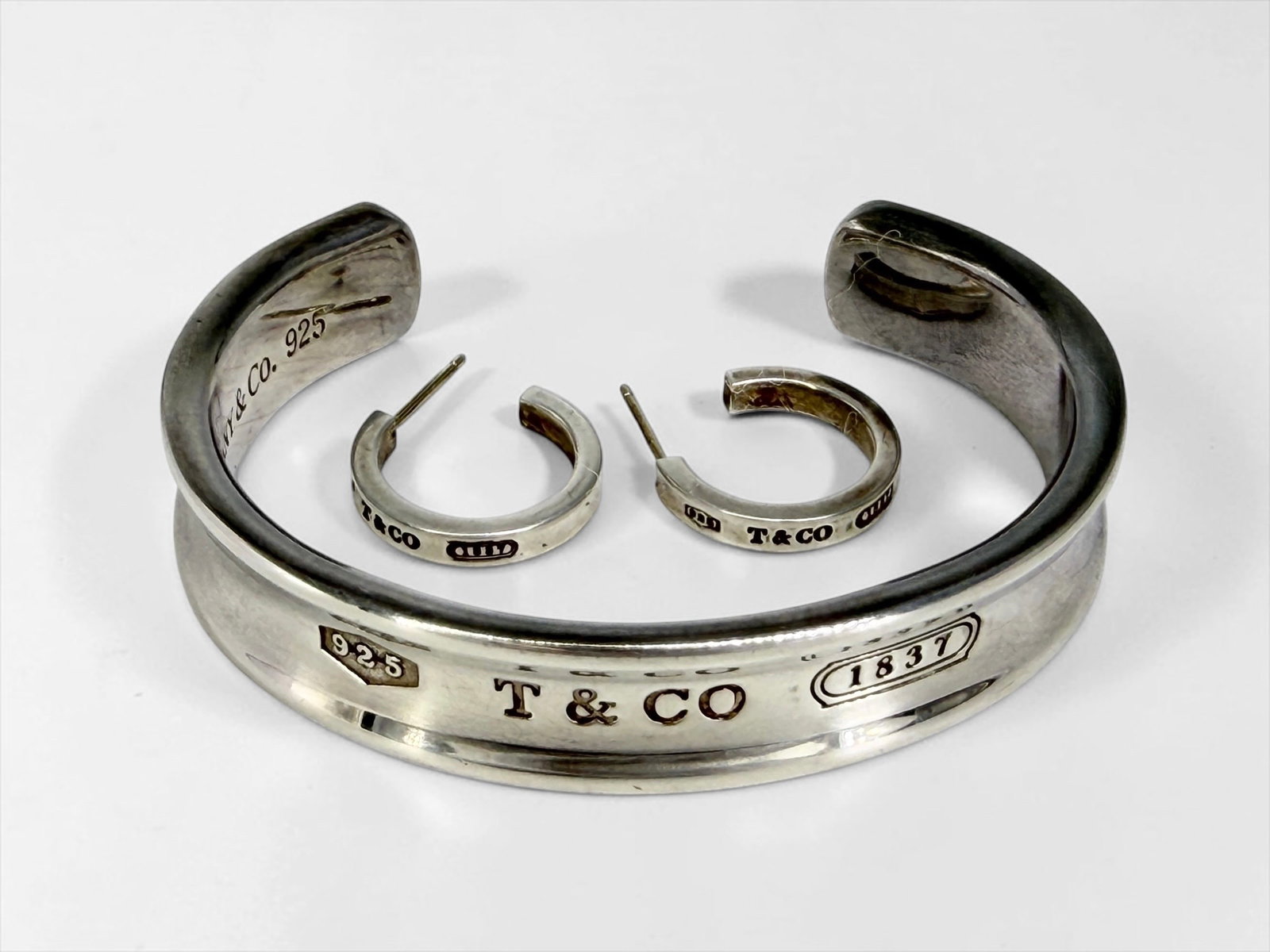 Tiffany & Co 1837 Sterling Cuff Bracelet & Earrings: Interior Diameter Of Cuff: Slightly over 2" Total Weight: 1.5 ozt Condition: Good with tarnishing and light surface scratches consistent with use