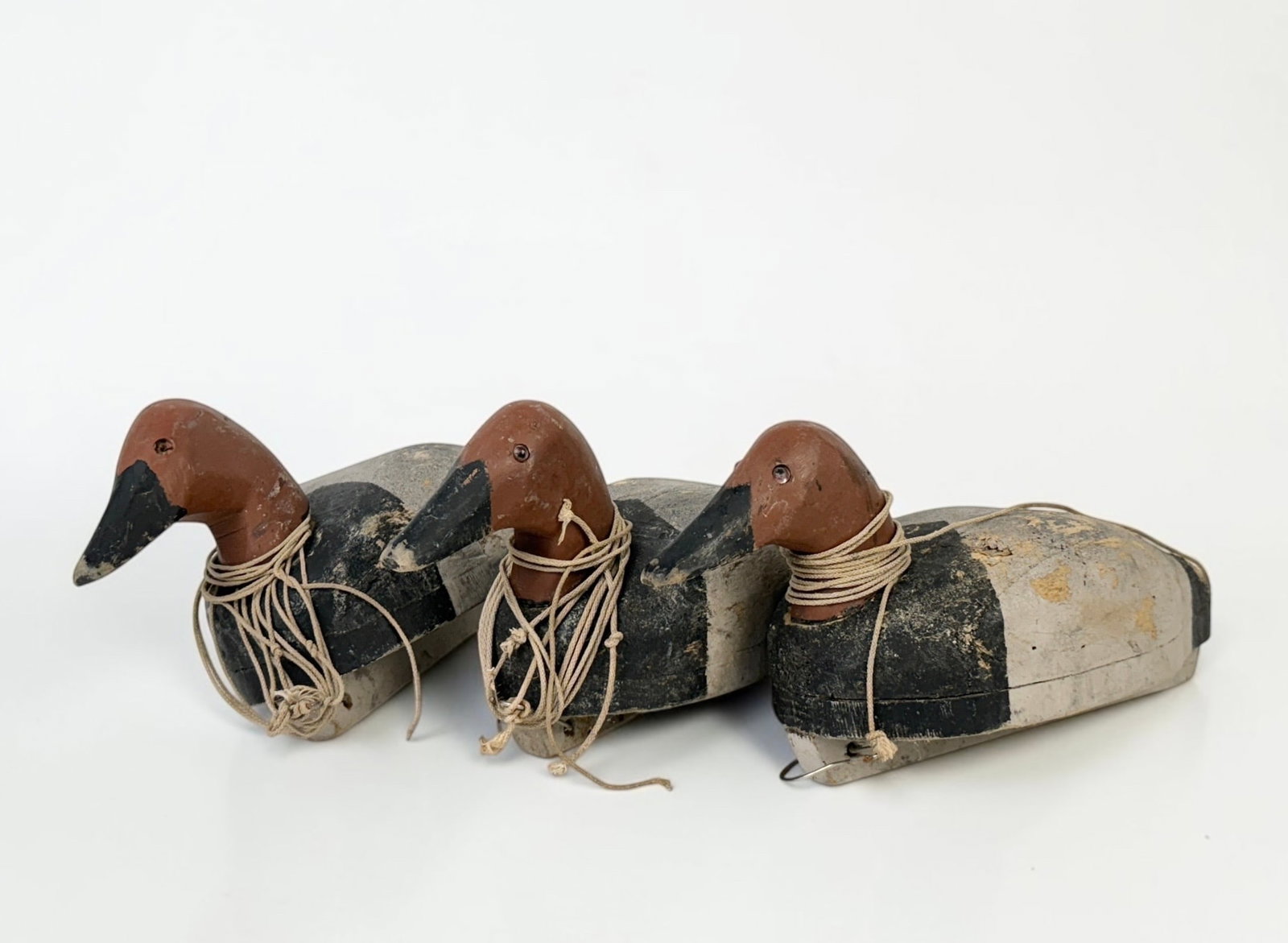 (3) Antique Wood Carved Duck Decoys: Dimensions: 8" x 16" x 6" Condition: Wear to the paint on all decoys. There are scratches and chips to the wood throughout. Several eye inlays are missing, and heads are lo