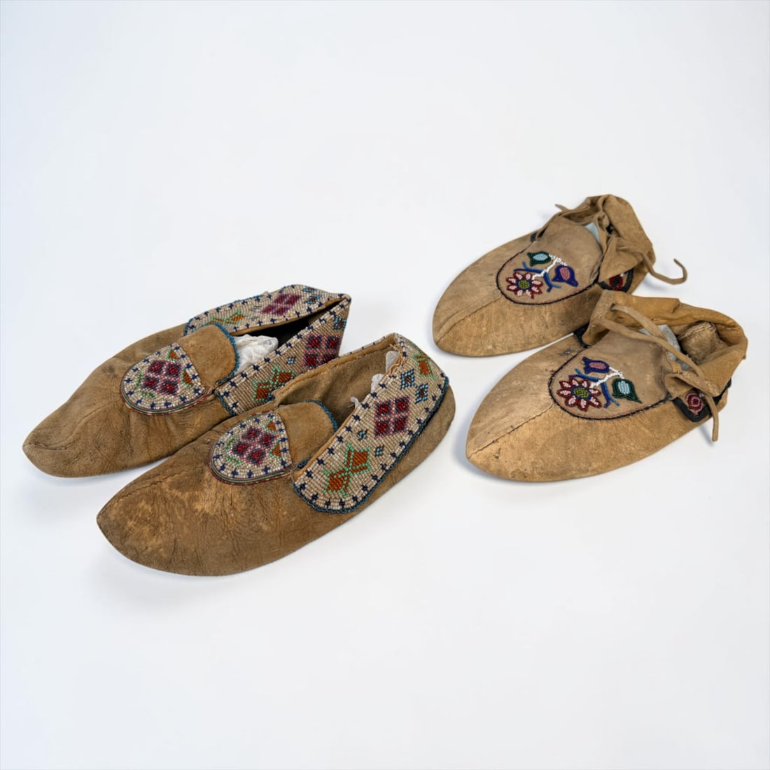 (2) Pairs of Native American Beaded Hide Moccasins (C): Largest Pair: about 11" long Condition: Wear and aging throughout both pairs. One pair have holes in the soles. Light wear to the beadwork. Signs of a past parasite infestation and h