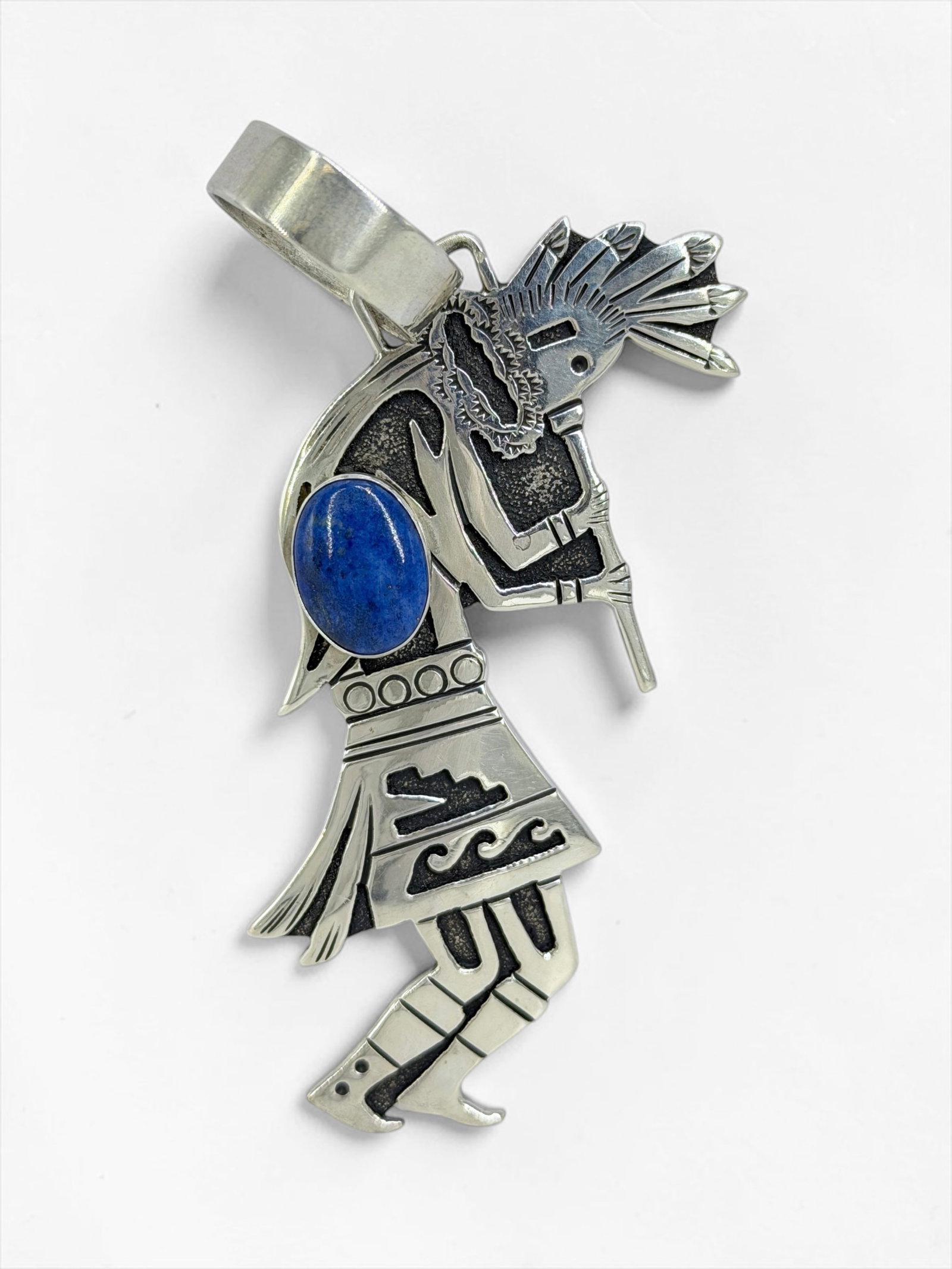 Tommy Singer Sterling Silver & Lapis Lazuli Kokopelli Pendant: Signed on reverse. Dimensions: 3" x 1 1/4" Total Weight: 19.15g Condition: In good condition. Artist Bio: Tommy Singer (c. 1940-2014) was a Navajo silv