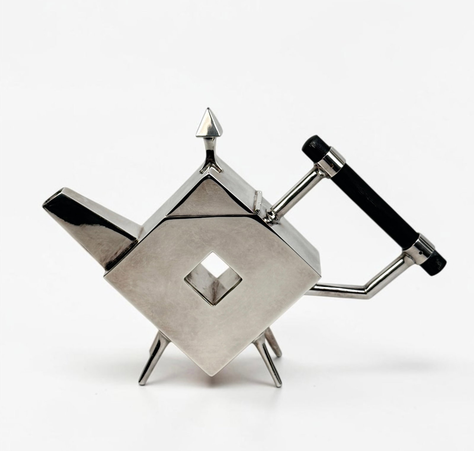 After Christopher Dresser Geometric Teapot: Silver-plated teapot with an ebonized wood handle, in the manner of Christopher Dresser’s designs for James Dixon & Sons. Dimensions: 10" Wide x 7" Tall x 2" Deep