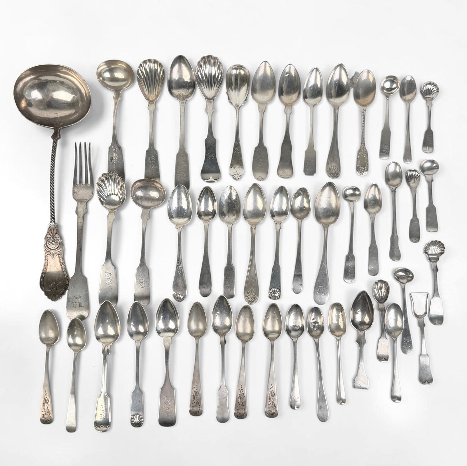 Large Group of Coin Silver Utensils: The lot consists primarily of spoons with one fork. Longest Piece: 10 1/2" (ladle) Total Weight: 25.3ozt Condition: The utensils have minor tarnishing throughout, but are in