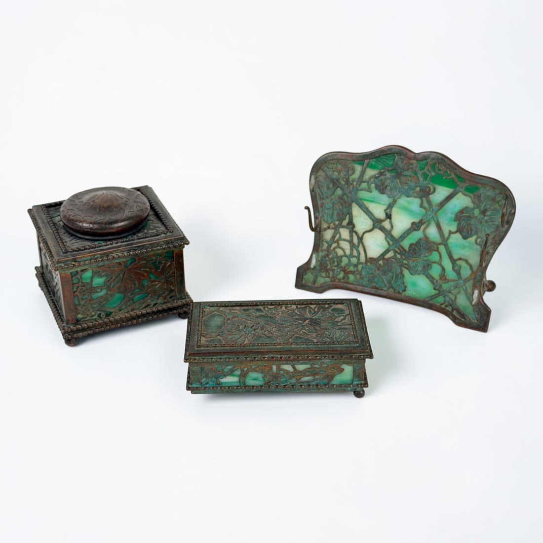 (3pc) Tiffany Studios "Grapevine" Desk Set: The lot includes an ink well, utility box, and a pen holder. Dimensions of Pen Holder: 5 1/4" Wide x 4 1/4" Tall x 2" Deep Condition: The bronze is patinated through