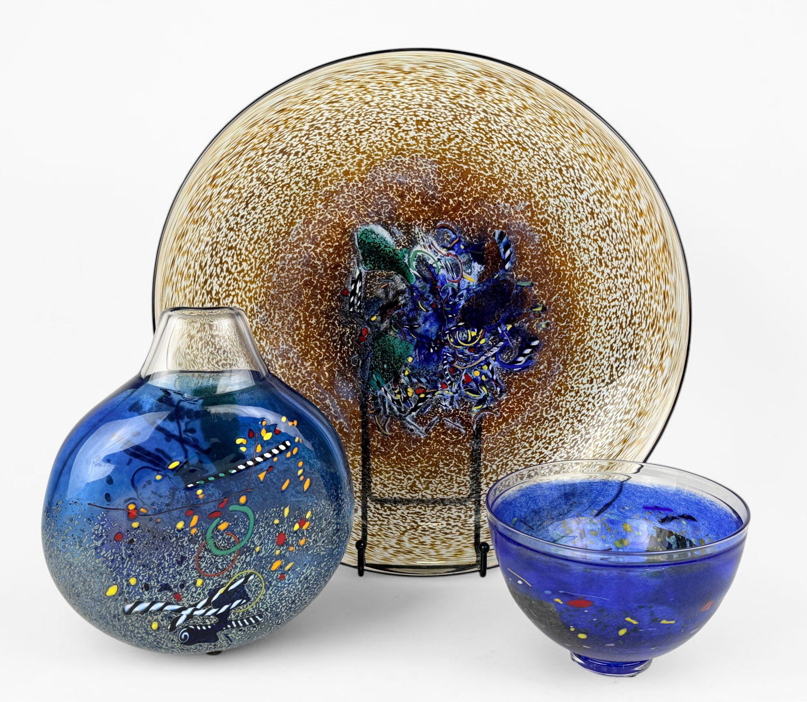 (3) Kosta Boda Art Glass Dishes: Lot includes 1 vase, 1 bowl, and 1 dish. All pieces are signed on the bottom. Dimensions of dish: 3" Tall x 15 1/4" Diameter Condition: All of the pieces are in ver