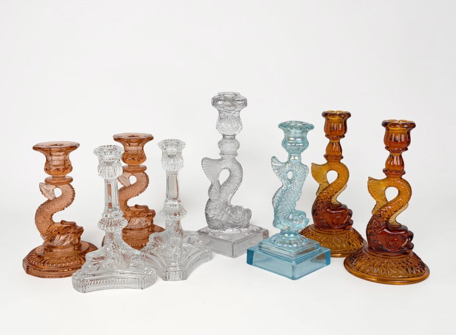 (8) "Dolphin" Glass Candlesticks: Includes candlesticks from Fenton, Cambridge Glass Co., and MMA. Dimensions: 11" Tallest Candlestick Condition: All candlesticks are in very good condition. Please see images 
