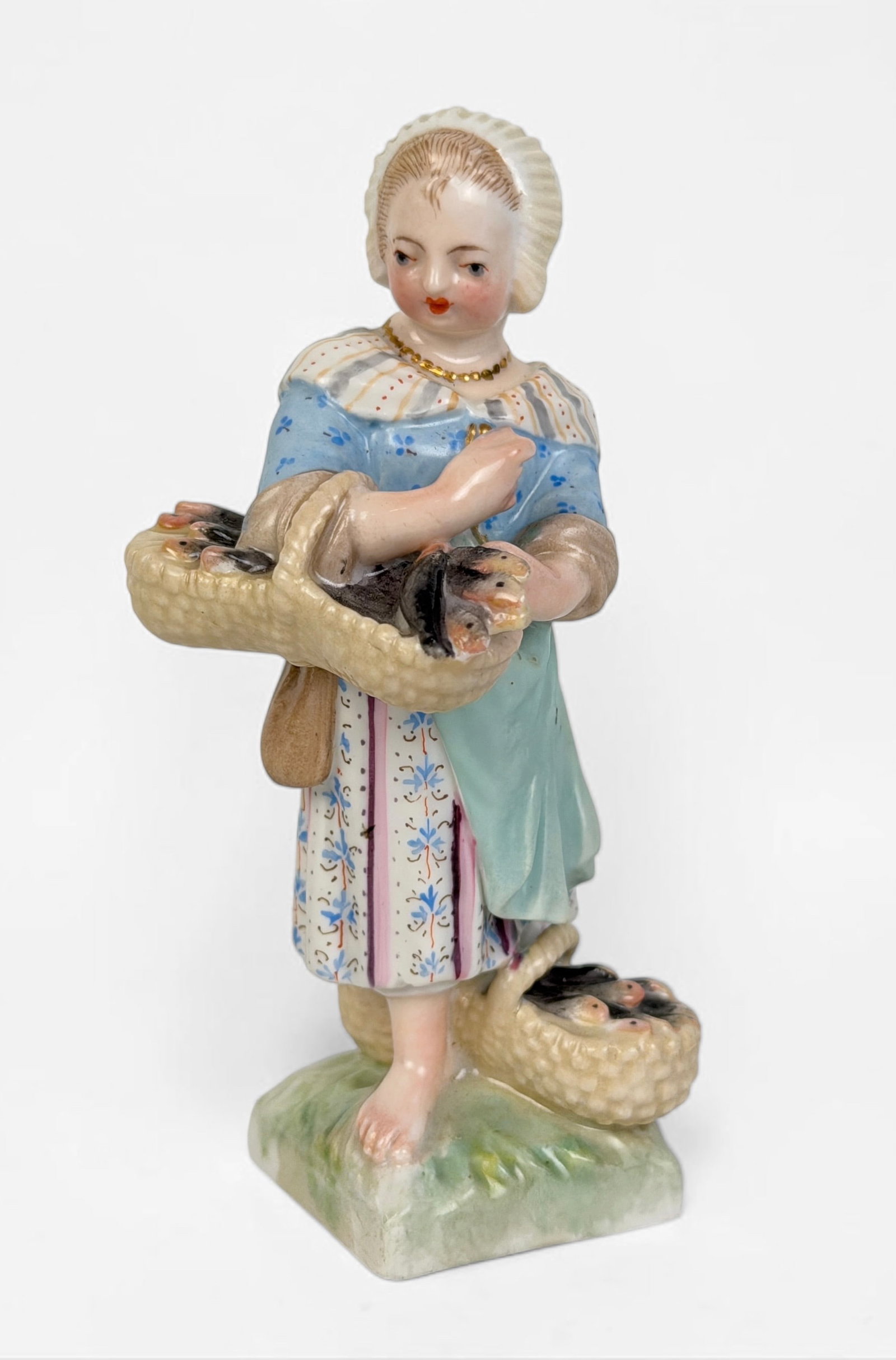 KPM 'Girl with Basket' Porcelain Figure: Marked on the bottom. Dimensions: 4 1/2" Tall x 2" Wide x 2" Deep Condition: Minor mark on the porcelain on the backside. No chips or cracks. About: The