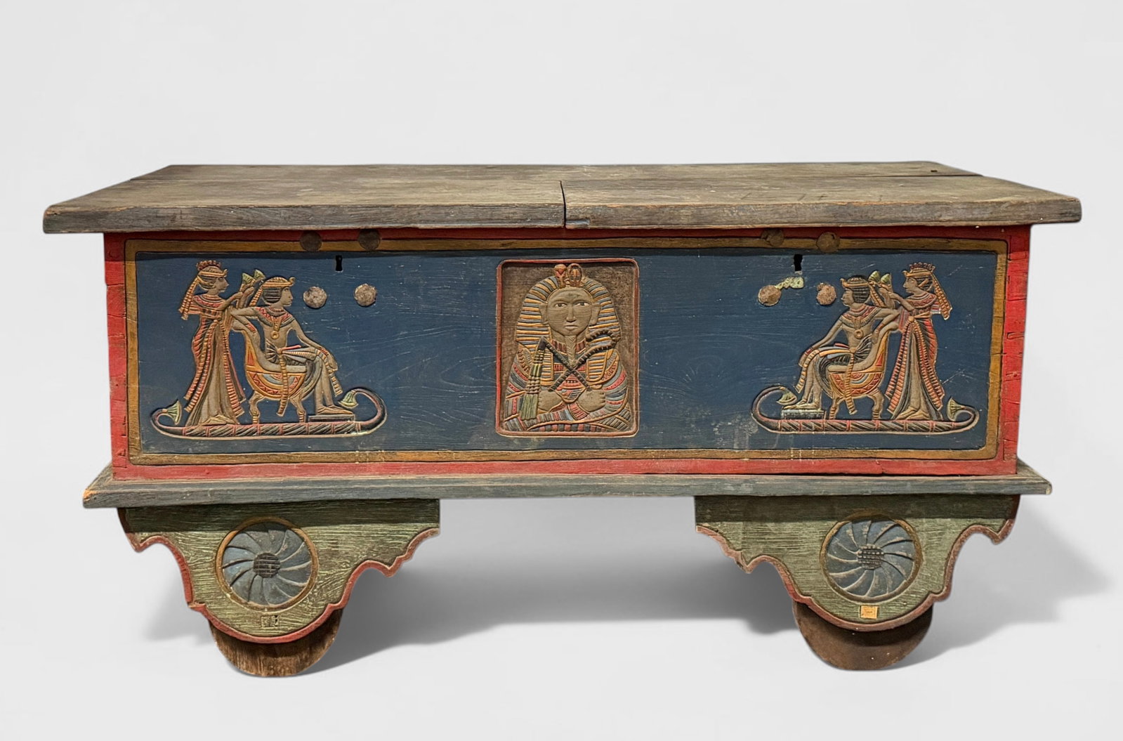 Antique Egyptian Wooden Chest on Wheels: Pharaoh Motif. Wooden wheels. Dimensions: 28 1/2" x 57 1/2" x 26 1/2" Condition: The top wood panels have extreme loss of pigment. The decorative panel on the side h