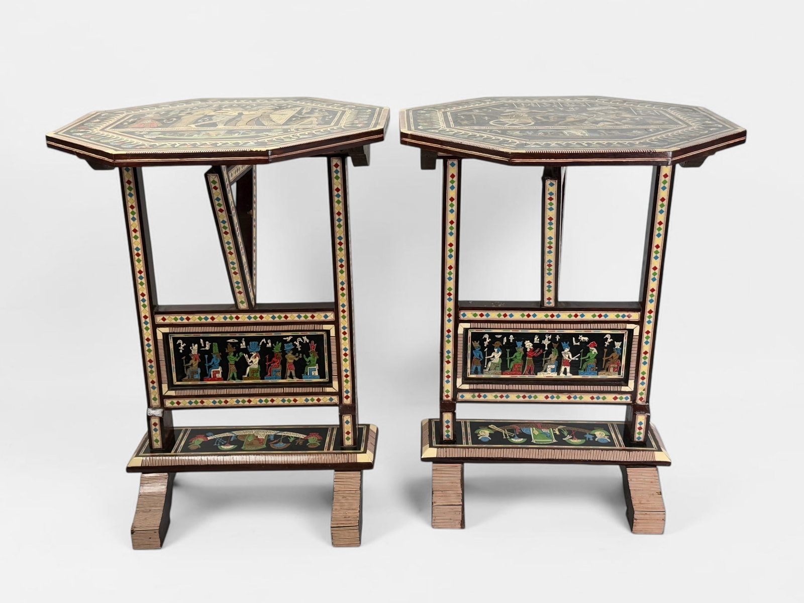 Pair of Egyptian Octagonal Inlaid Tables: The tables feature a musician's motif and a chariot motif. Dimensions: 24 1/2" Tall x 18 1/2" Wide x 18 1/2" Deep Condition: The table tops fold down