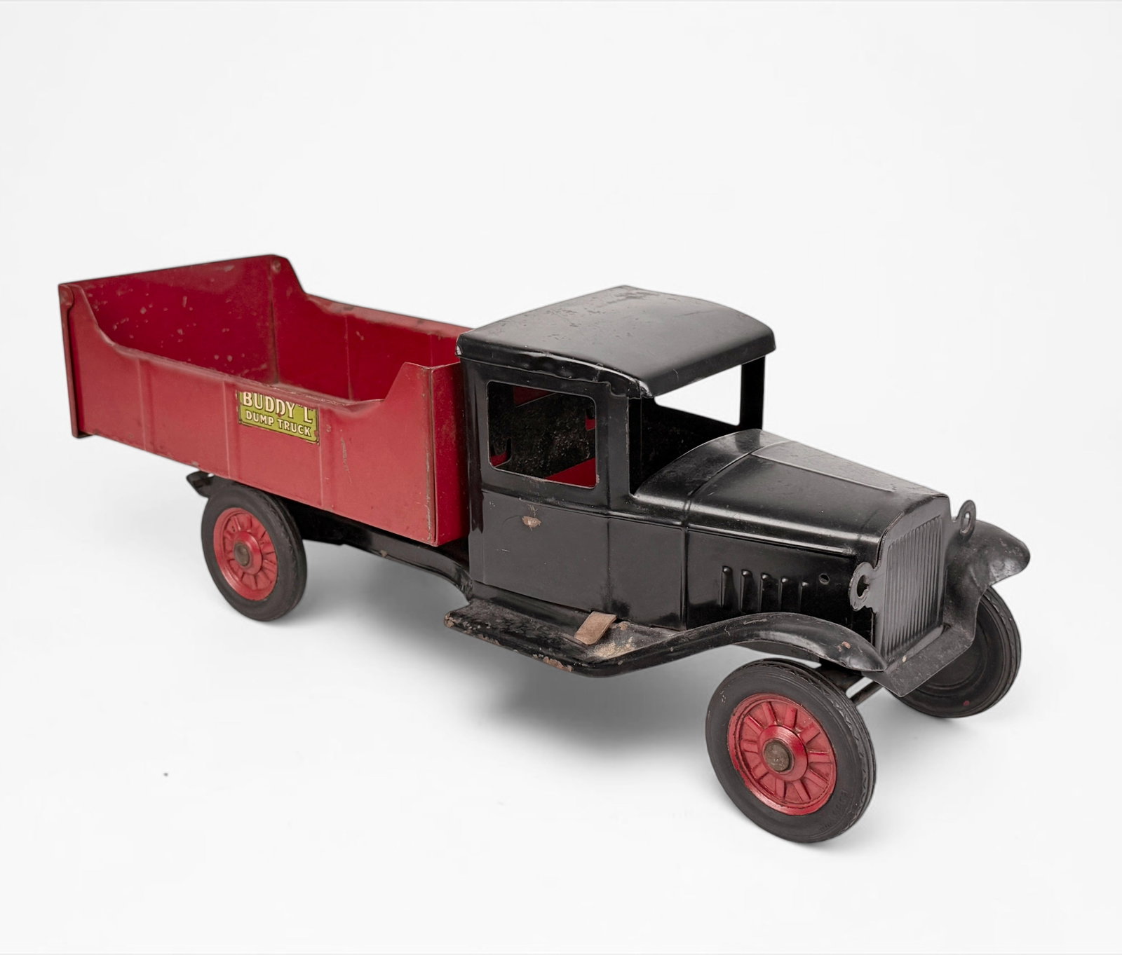 Vintage Buddy "L" Dump Truck Toy: Dimensions: 7 1/4" x 20" x 6" Condition: There is loss of pigment and rust throughout, consistent with the toy's age. The front wheels struggle to turn fully. See