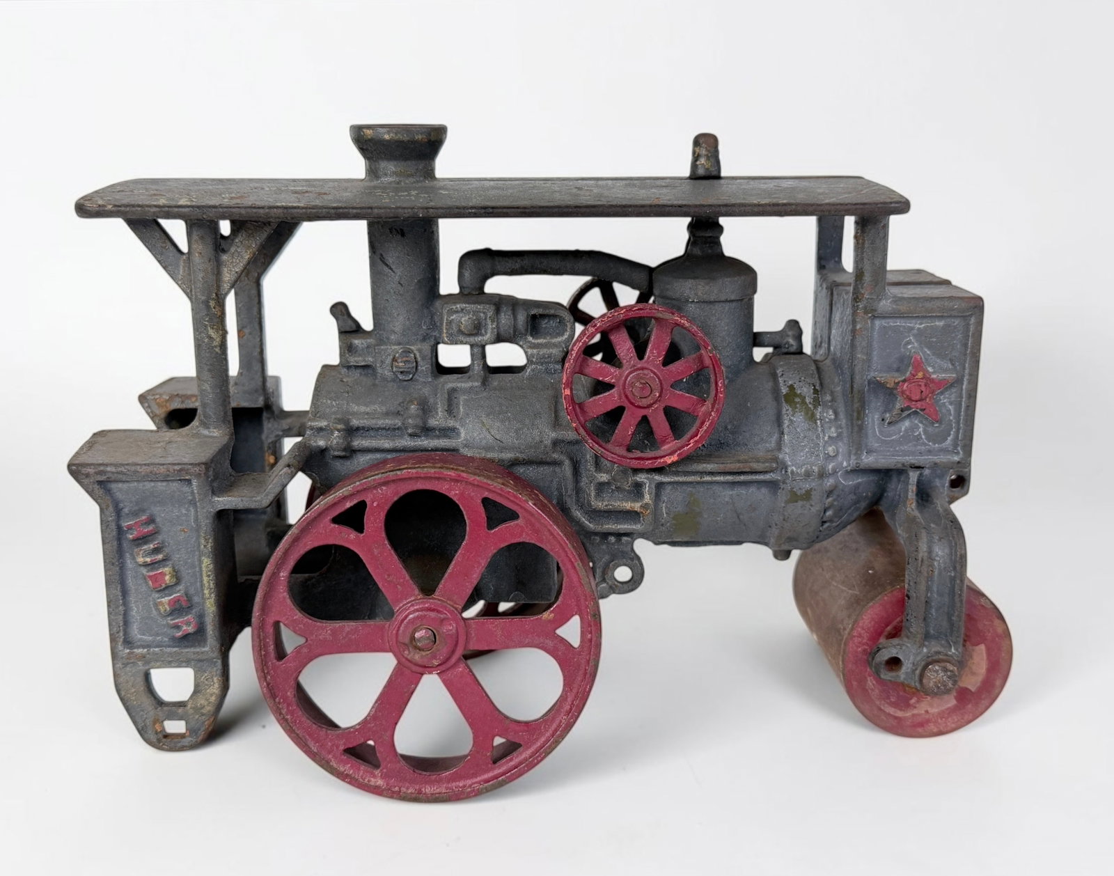 Vintage Cast Iron Huber Steam Road Roller Toy: Dimensions: 5 1/2" x 7 1/2" x 3 1/2" Condition: Wear to the red pigment and rust to the cast iron, consistent with the age of the toy. See images for details. 