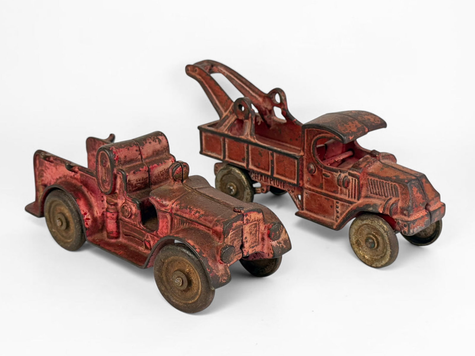 (2) Antique Cast Iron Toy Cars (E): Includes brands Champion and Hubley. Dimensions of Largest: 4" x 8 1/4" x 2" Condition: Rust throughout the cars, with minor loss of red pigment. Otherwise, th